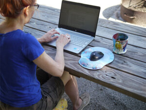 red-headed woman with laptop at picnic table Jane McBay