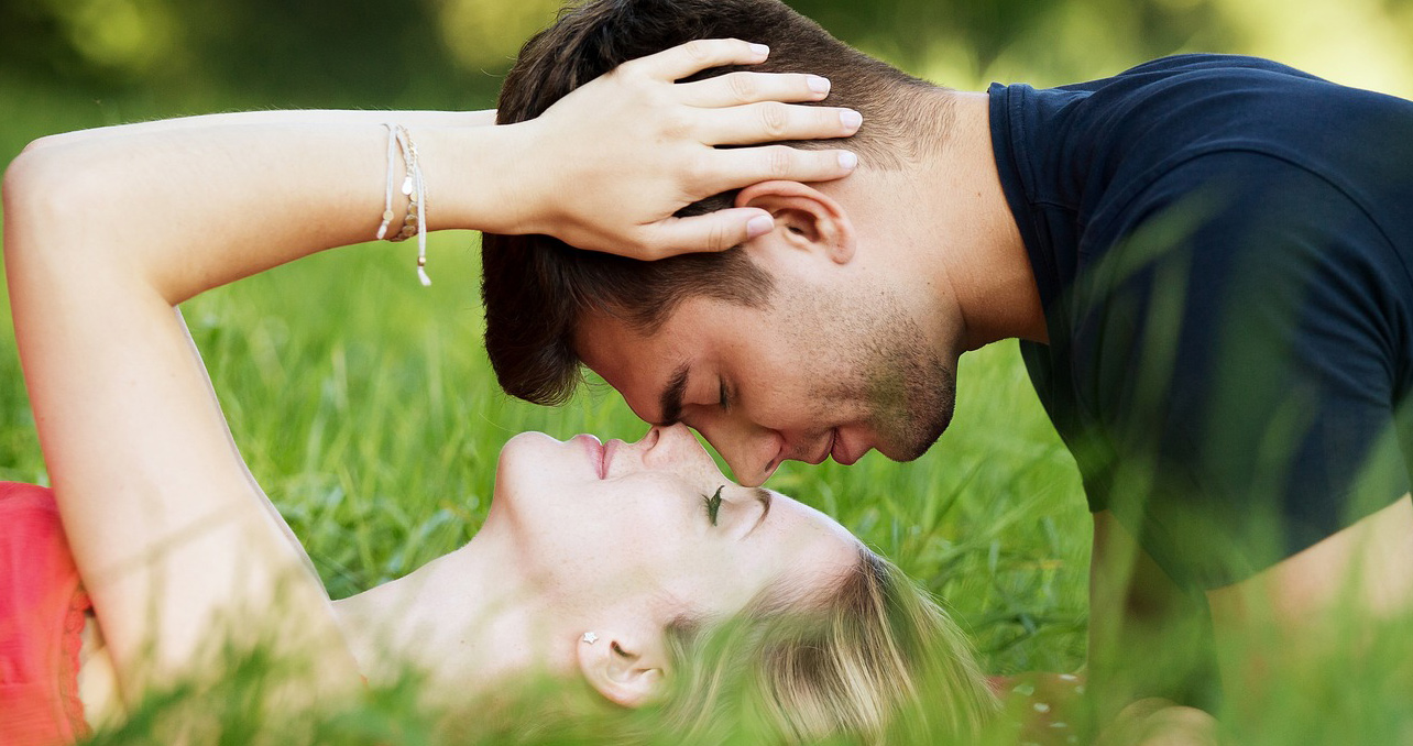 man and woman on grass, face to face